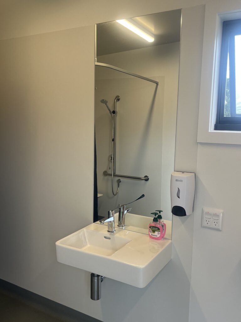 Wall-mounted basin with clear space underneath, allowing closer access for a wheelchair user